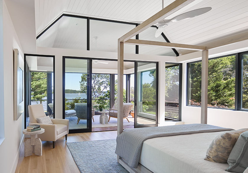 The owner’s bedroom opens to a screened porch beneath a raised, wood-paneled ceiling.