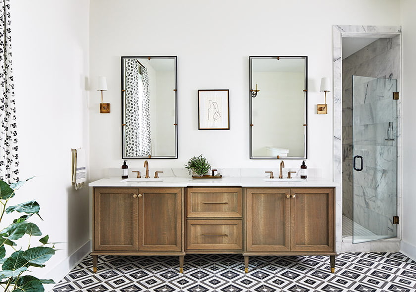 Owners’ bath with white oak vanity topped with quartz, a marble tile floor and Visual Comfort sconces.