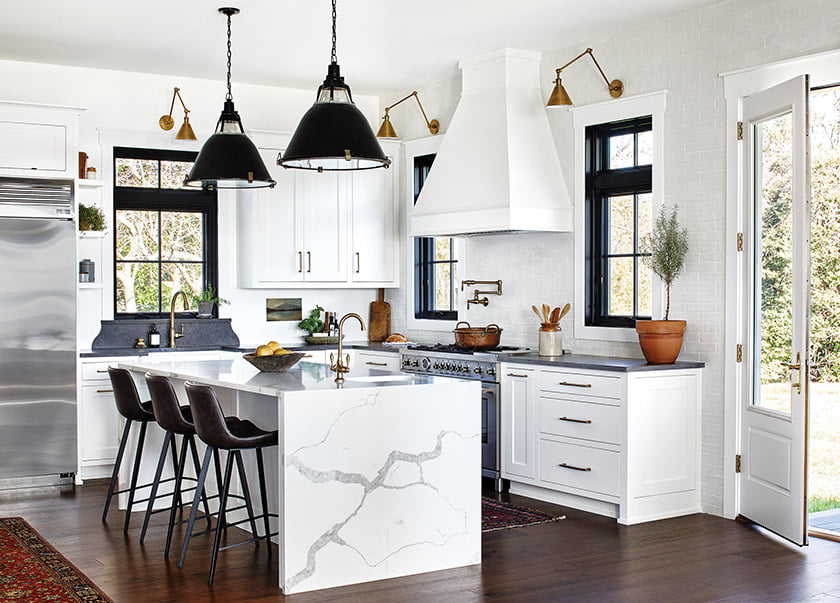 Kitchen cabinetry with gray quartz peripheral counters.  Arhaus stools with vintage German factory pendants.