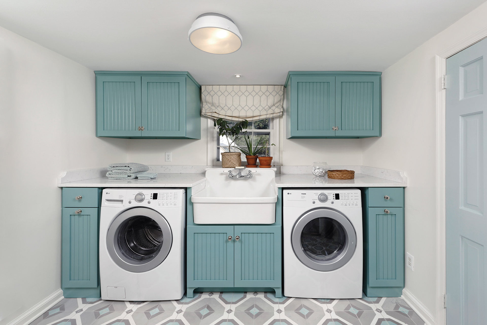 Low-slung laundry sink centers a wall of cabinets and appliances in the laundry room.